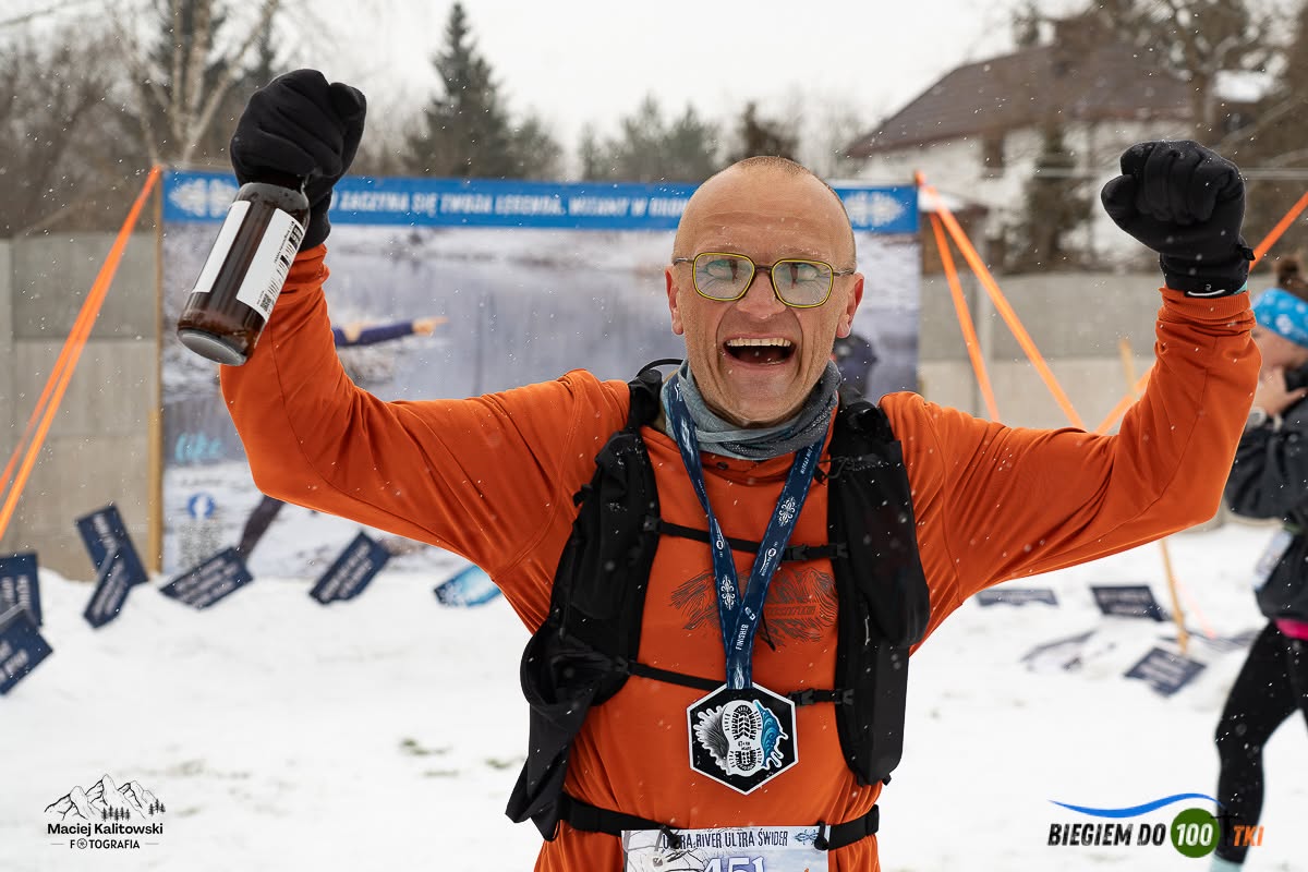 Finiszer URUŚ z medalem i piwem Świderman unosi ręce w geście triumfu
