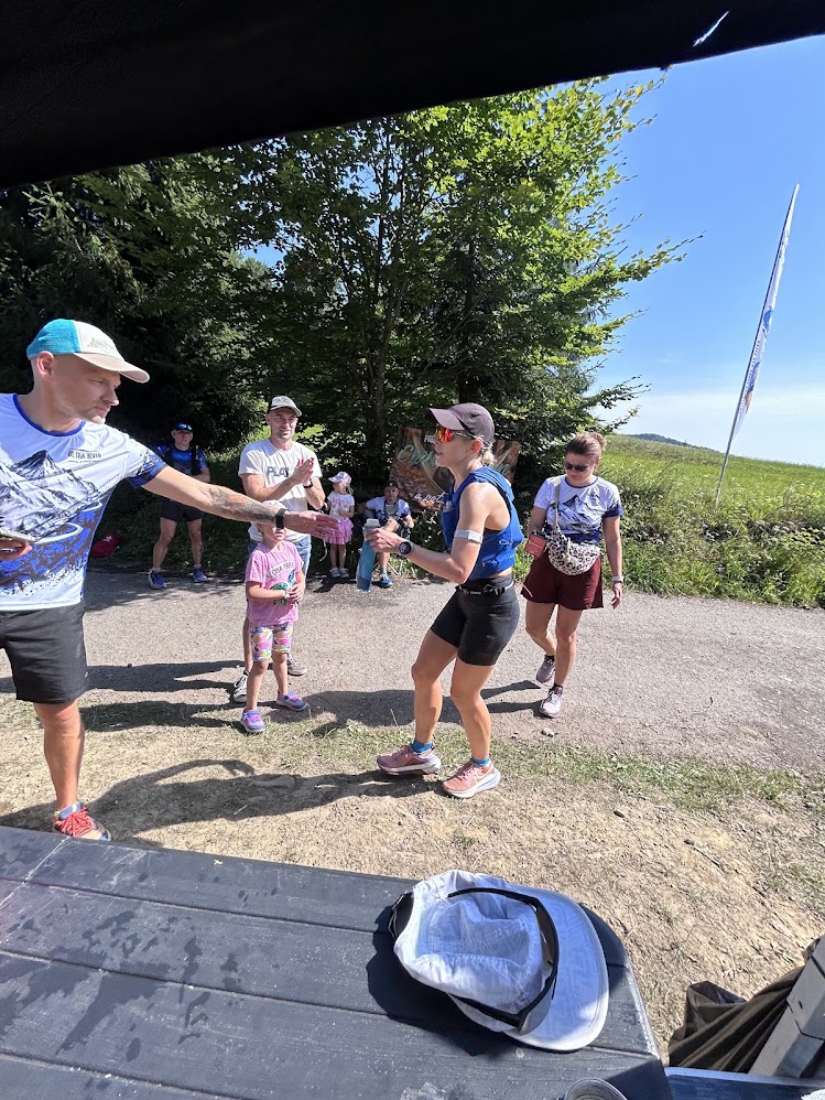Wolontariusz Ultra River podaje kubek biegaczce wbiegającej na punkt