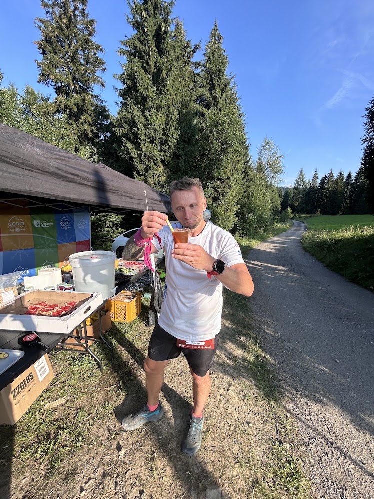 Biegacz z kubkiem tonic espresso na punkcie odżywczym Gorce Ultra Trail
